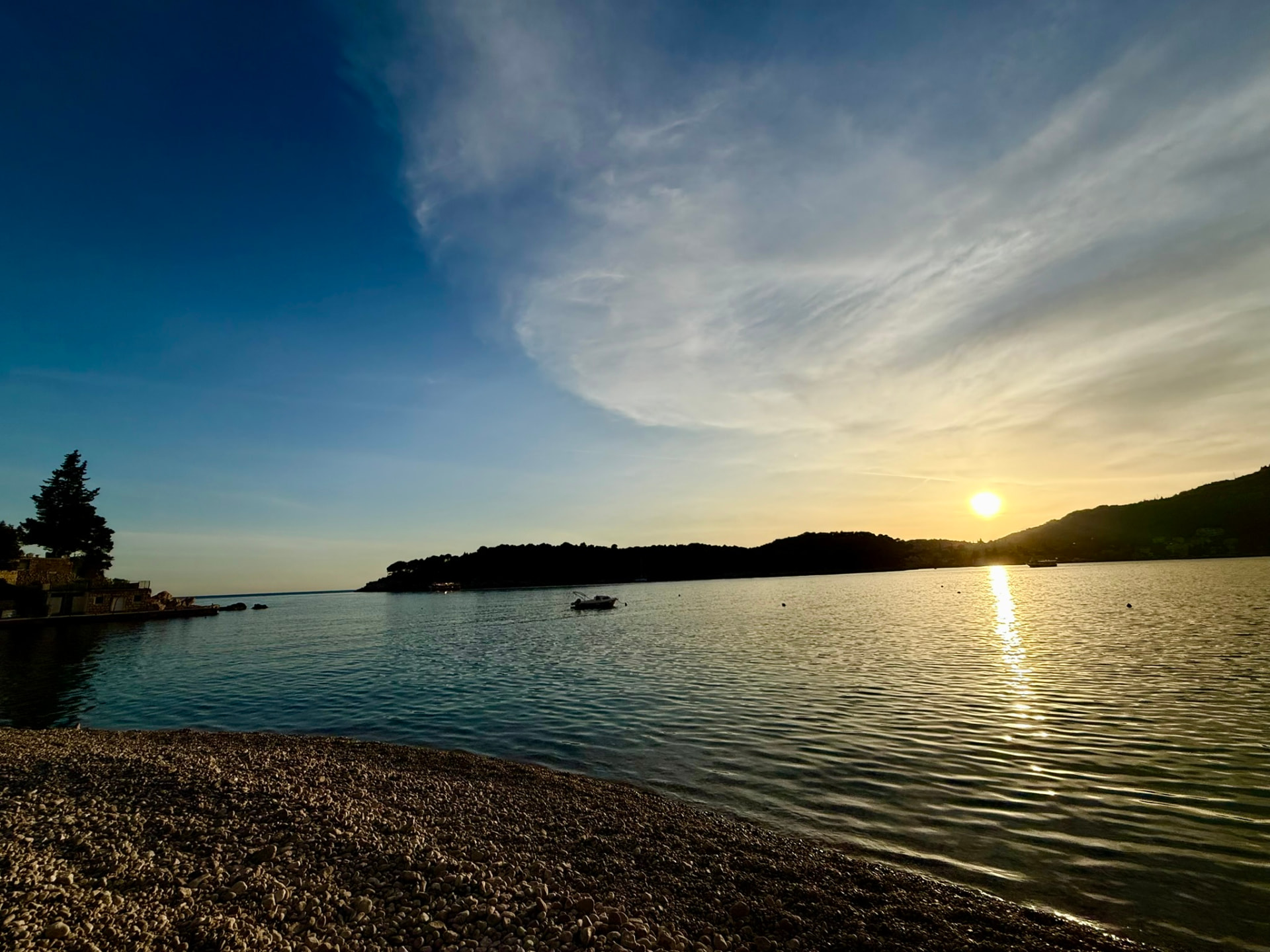 Sunset over a pebble beach and a calm bay near the retreat