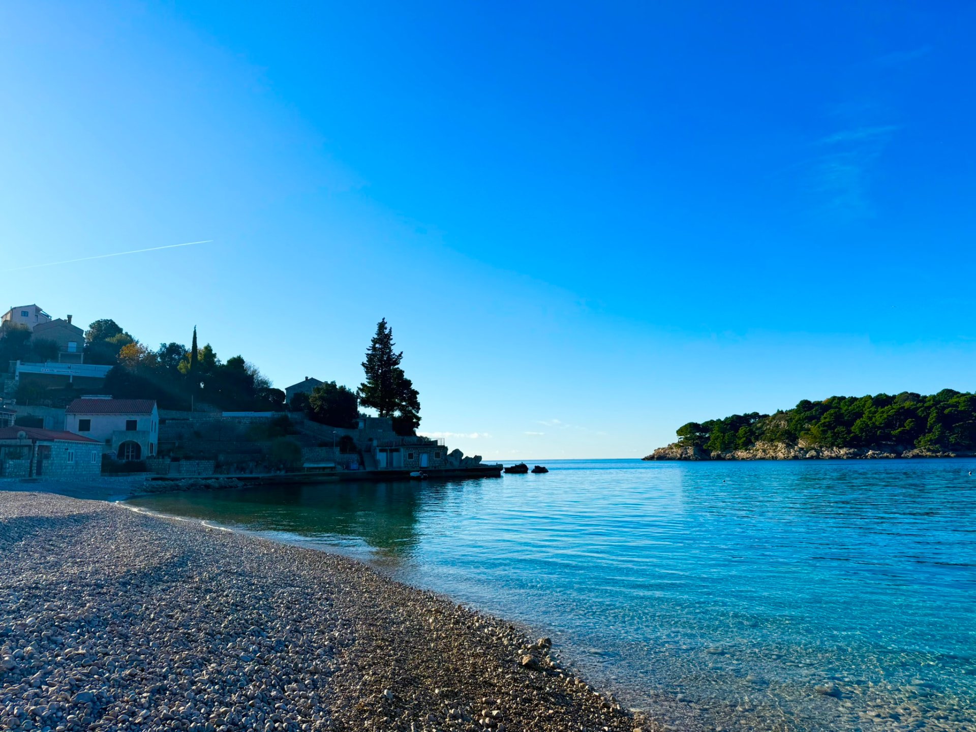 The pebble beach and calm turquoise bay beside the villa